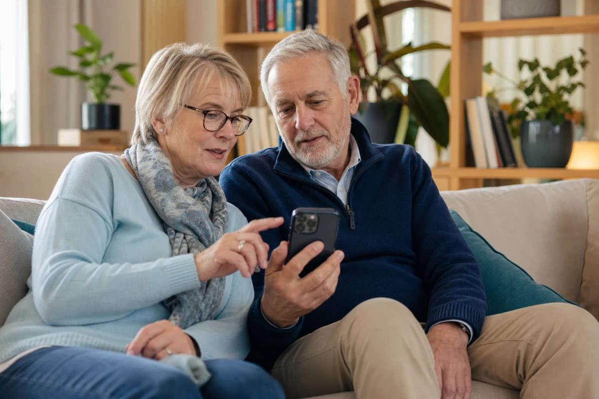 Two older residents using a smartphone together in a community lounge